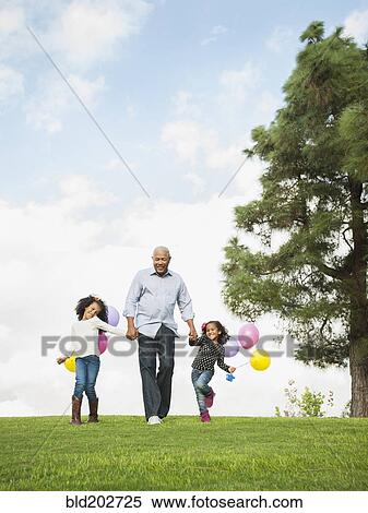 Stock Photography - Man walking with granddaughters in park. Fotosearch
