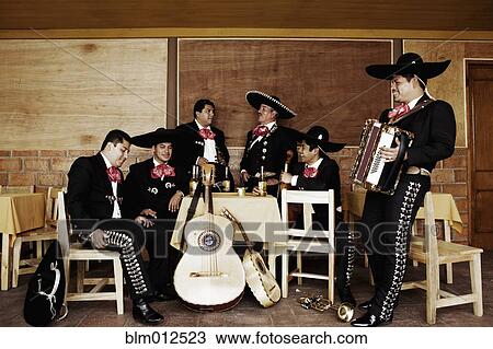 Stock Image - Mariachi musicians relaxing together in restaurant. Fotosearch