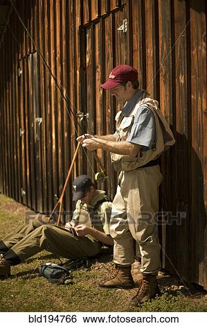 Stock Photograph - Men adjusting fishing rods. Fotosearch