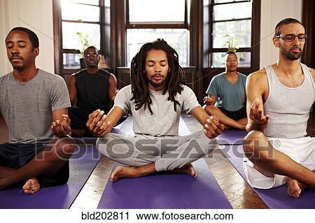 Stock Image - Men meditating in yoga class. Fotosearch