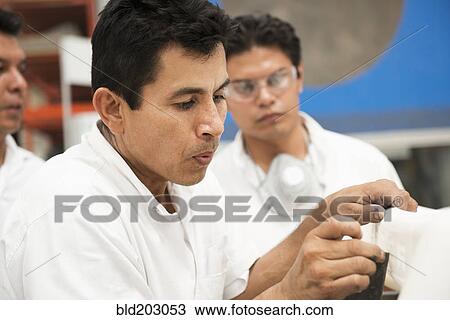Stock Image - Men working in manufacturing plant. Fotosearch