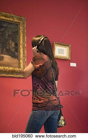 Stock Image - Middle Eastern woman admiring painting in museum. Fotosearch