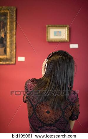 Stock Image - Middle Eastern woman admiring painting in museum. Fotosearch