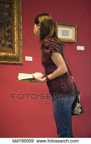 Stock Photo - Middle Eastern woman admiring painting in museum. Fotosearch