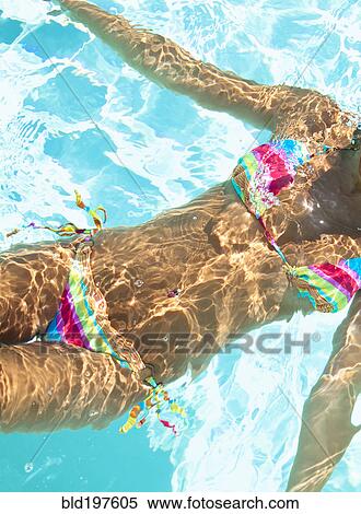 Stock Photography - Midsection of mixed race woman swimming in swimming pool. Fotosearch