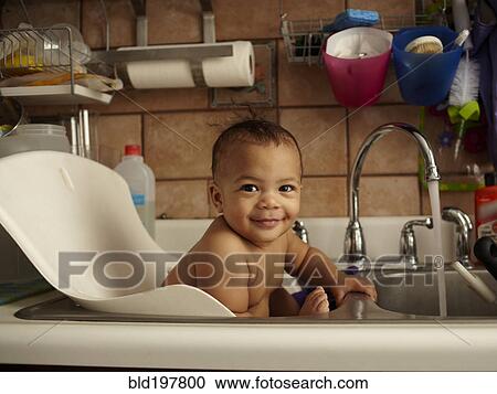 Stock Image - Mixed race baby girl bathing in sink. Fotosearch