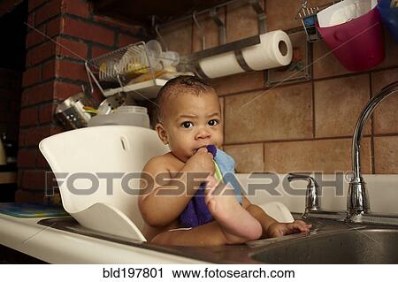 Stock Image - Mixed race baby girl bathing in sink. Fotosearch