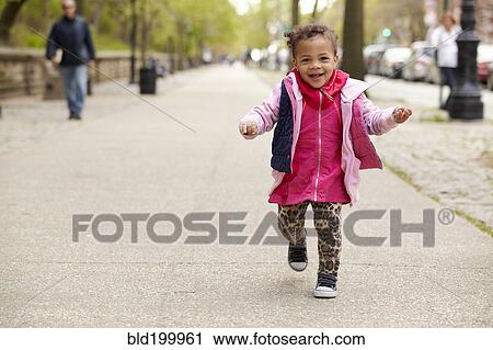 Stock Image - Mixed race baby girl walking on sidewalk. Fotosearch
