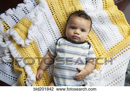 Stock Image - Mixed race baby laying on blanket. Fotosearch