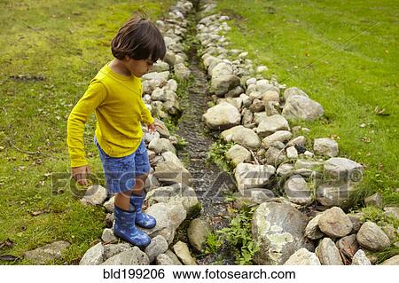 Mixed race boy crossing stream View Large Photo Image Stock Photograph - Mixed race boy crossing stream. Fotosearch