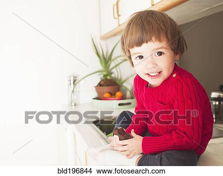 Picture - Mixed race boy eating brownie. Fotosearch