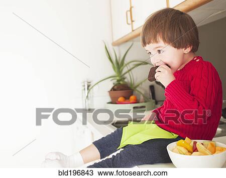 Stock Image - Mixed race boy eating brownie. Fotosearch