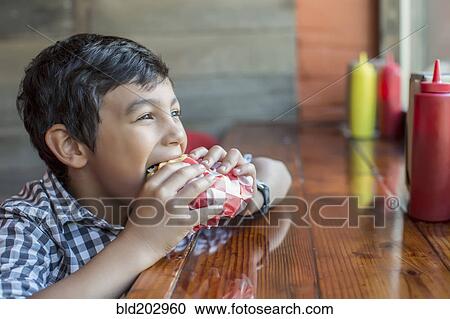 Mixed race boy eating burger in restaurant View Large Photo Image Stock Image - Mixed race boy eating burger in restaurant. Fotosearch