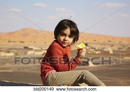 Stock Photo - Mixed race boy eating fruit. Fotosearch