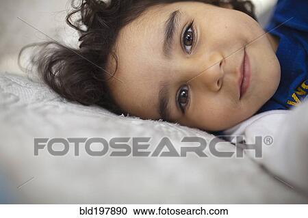 Stock Image - Mixed race boy laying in bed. Fotosearch