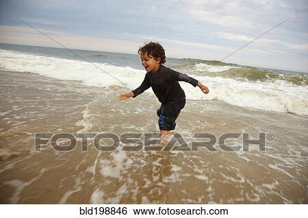 Stock Photograph - Mixed race boy playing in ocean waves. Fotosearch