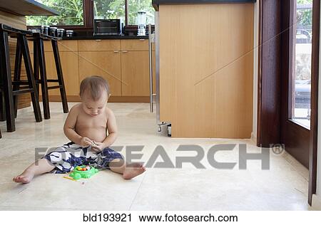 Stock Image - Mixed race boy playing with toys on floor. Fotosearch