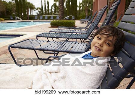 Mixed race boy reclining on lounge chair at poolside View Large Photo Image Stock Photo - Mixed race boy reclining on lounge chair at poolside. Fotosearch