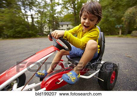 Stock Photo - Mixed race boy riding toy car. Fotosearch