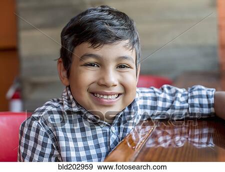 Stock Photo - Mixed race boy sitting in restaurant. Fotosearch