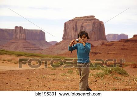Stock Image - Mixed race boy taking pictures in Monument Valley. Fotosearch