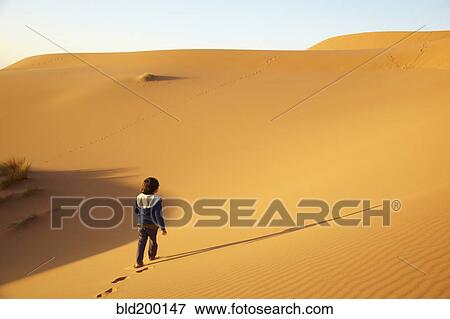 Stock Photo - Mixed race boy walking in desert. Fotosearch