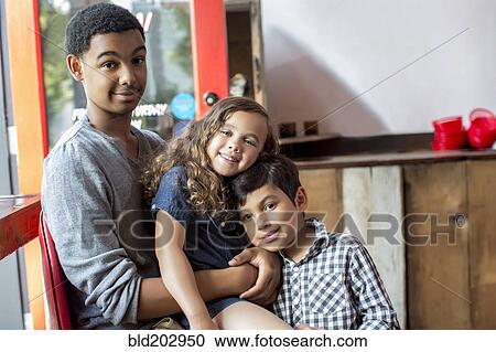 Stock Image - Mixed race brothers and sister smiling together. Fotosearch