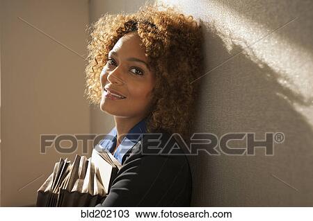 Stock Image - Mixed race business woman holding folders. Fotosearch