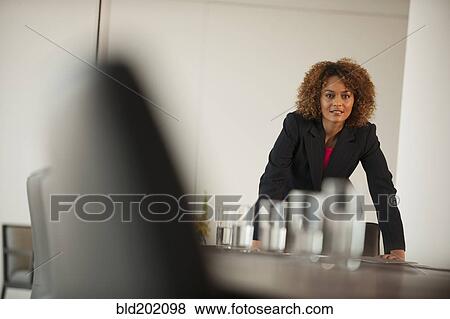Stock Photo - Mixed race businesswoman leaning on conference table. Fotosearch