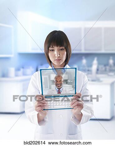 Picture - Mixed race doctor using digital tablet in a lab. Fotosearch