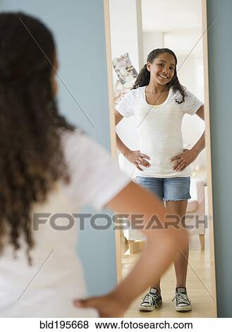 Mixed race girl checking reflection in mirror View Large Photo Image Stock Photo - Mixed race girl checking reflection in mirror. Fotosearch