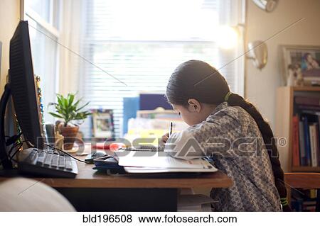 Stock Photo - Mixed race girl doing homework at desk. Fotosearch