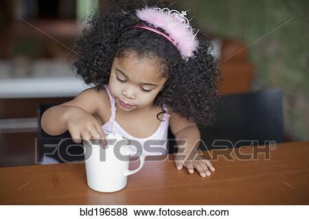 Stock Photo - Mixed race girl drinking hot chocolate. Fotosearch