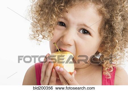 Stock Photograph - Mixed race girl eating apple. Fotosearch