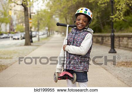 Stock Photography - Mixed race girl holding push scooter on sidewalk. Fotosearch