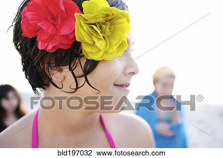 Stock Image - Mixed race girl on beach with flowers in her hair. Fotosearch