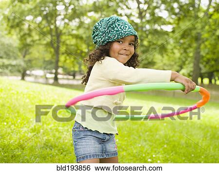 Mixed race girl playing with plastic hoop View Large Photo Image Stock Photograph - Mixed race girl playing with plastic hoop. Fotosearch