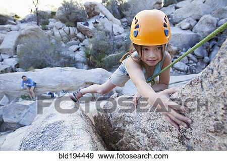 Stock Photo - Mixed race girl rock climbing. Fotosearch