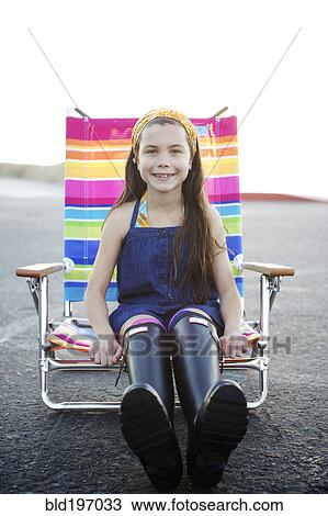 Stock Image - Mixed race girl sitting in lounge chair. Fotosearch