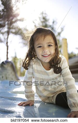 Picture - Mixed race girl sitting outdoors. Fotosearch