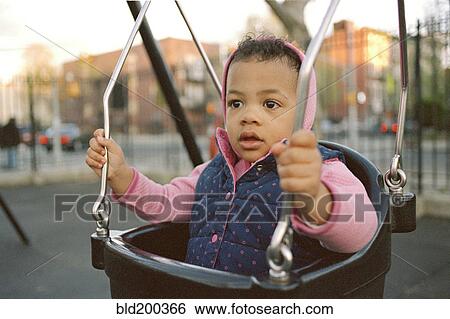 Mixed race girl swinging in playground View Large Photo Image Stock Photograph - Mixed race girl swinging in playground. Fotosearch