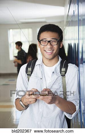 Stock Photo - Mixed race high school student text messaging on cell phone. Fotosearch