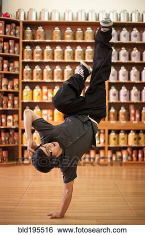 Stock Photograph - Mixed race man doing handstand in shop. Fotosearch
