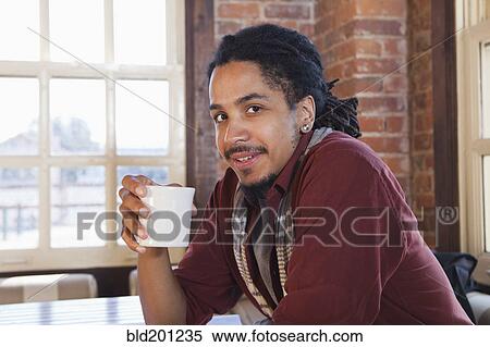 Mixed race man drinking coffee in coffee shop View Large Photo Image Stock Photography - Mixed race man drinking coffee in coffee shop. Fotosearch