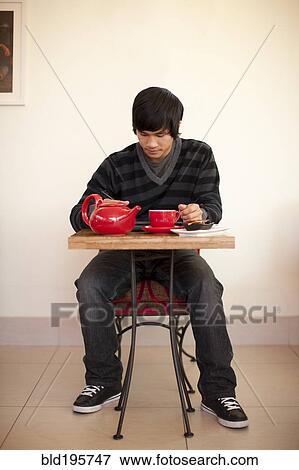 Mixed race man drinking tea and using digital tablet at cafe View Large Photo Image Stock Photo - Mixed race man drinking tea and using digital tablet at cafe. Fotosearch