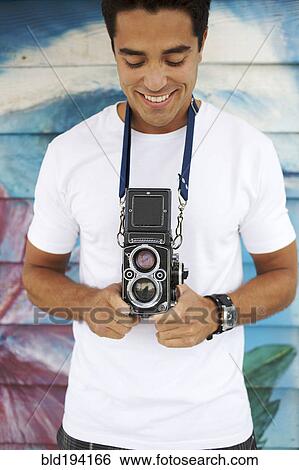 Mixed race man holding old-fashioned camera View Large Photo Image Stock Photograph - Mixed race man holding old-fashioned camera. Fotosearch