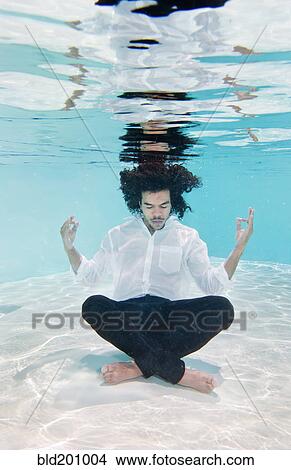 Picture - Mixed race man in clothes underwater in swimming pool. Fotosearch