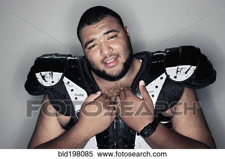 Stock Photography - Mixed race man in football shoulder pads. Fotosearch