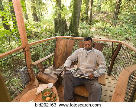 Stock Image - Mixed race man reading book on deck. Fotosearch