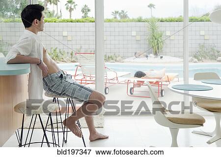 Stock Photo - Mixed race man sitting on bar stool. Fotosearch